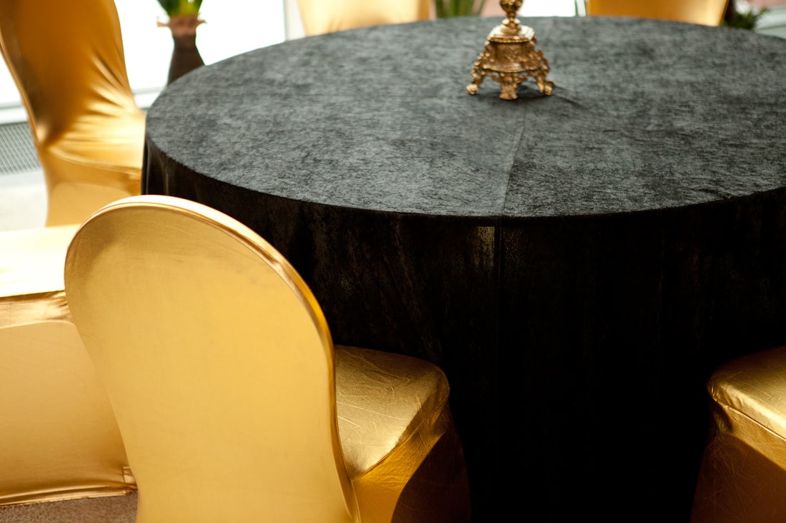 Tuolit, kultaiset tuolihuput, pöydät ja mustat pöytäliinat vuokralle.