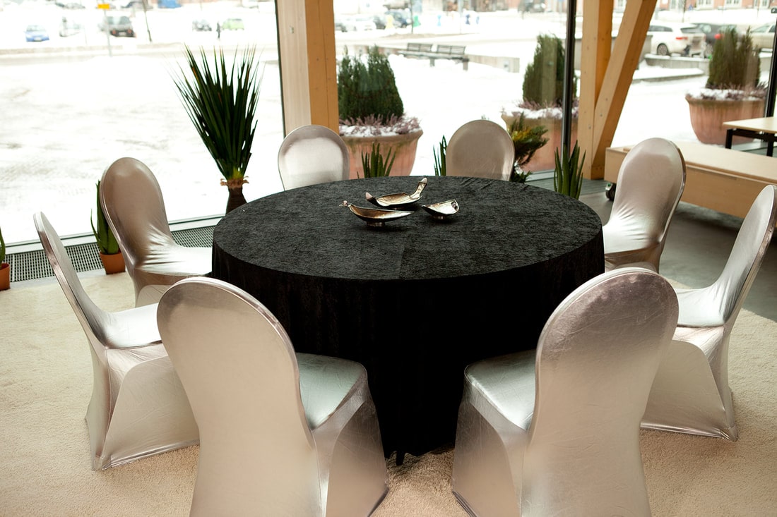 Pyöreä pöytä, musta pöytäliina ja tuolihuput vuokralle.